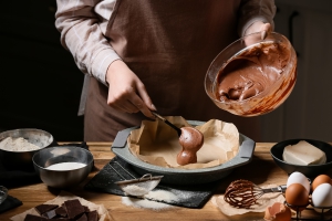Woman preparing chocolate brownie at kitchen table, closeup